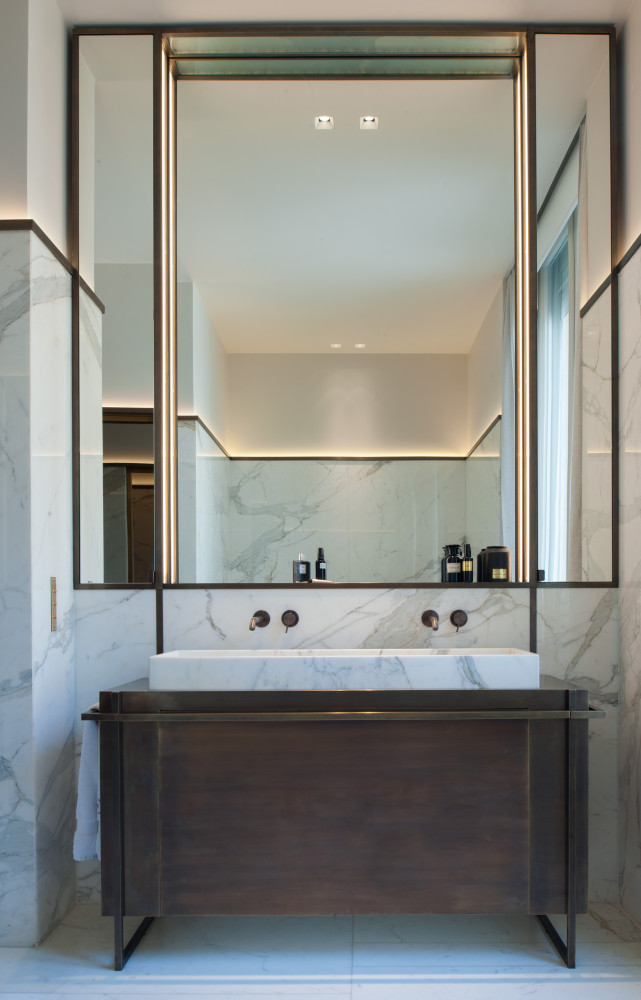 Dans la salle de bain très graphique en marbre de Calacatta, meuble, vasque et miroir ont été...