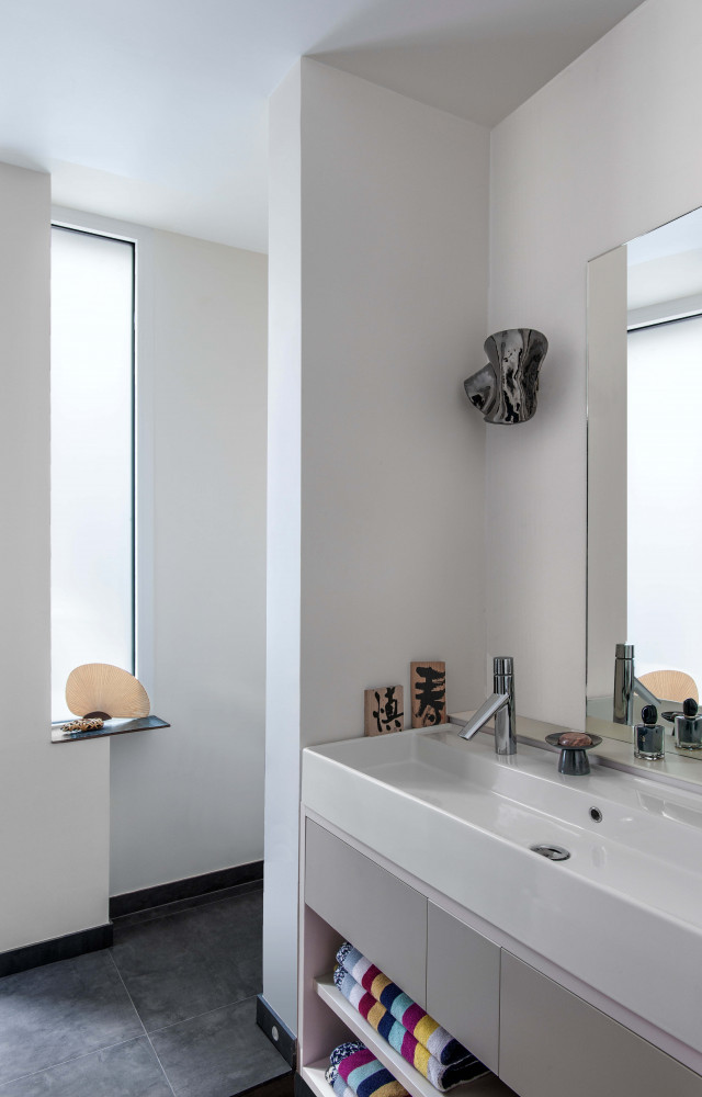 Dans la salle de bain éclairée par une meurtrière, appliques en céramique ondulée brun cuivré signées Armelle...