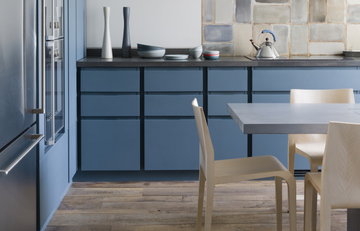 Les aménagements sur-mesure de cette cuisine, en bois peint en bleu mat et vernis, contrastent avec le sol en chêne massif.