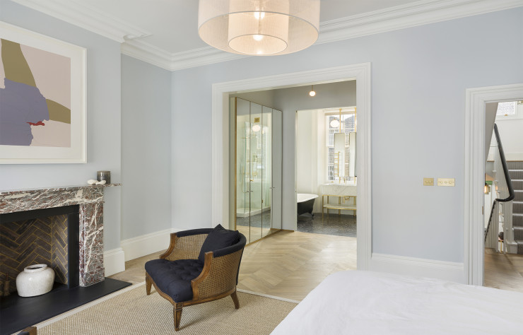 La chambre principale de la suite au 1er étage : la cheminée en marbre chinée à Londres apporte du caractère à la pièce aux murs clairs et au parquet en chevron.