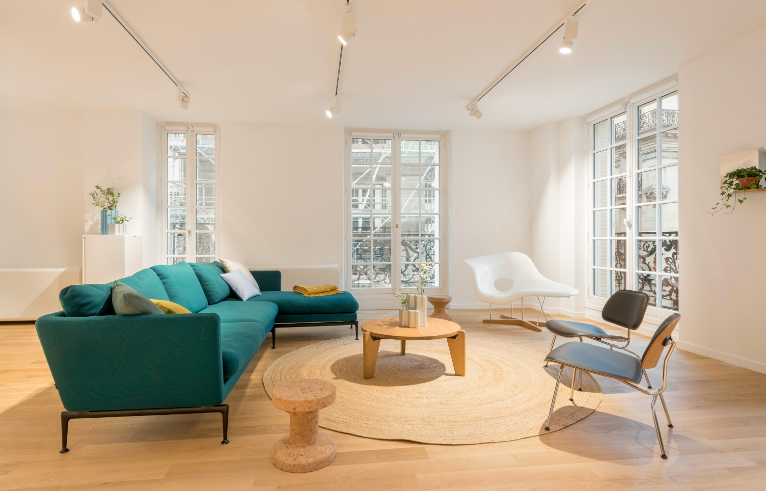 Le parquet clair et les murs et plafonds uniformément blancs mettent en valeur le mobilier coloré. Canapé...