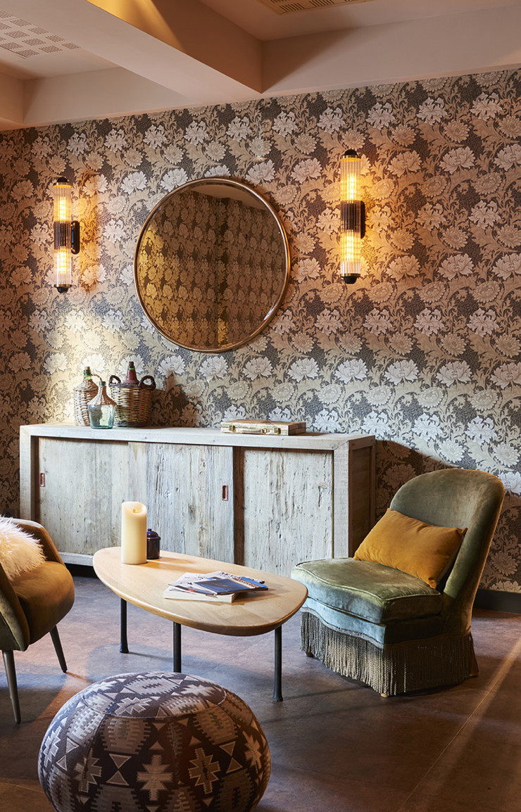 Dans un des salons, des appliques à l’allure indus’ illuminent un papier peint aux motifs dessinés par William Morris.