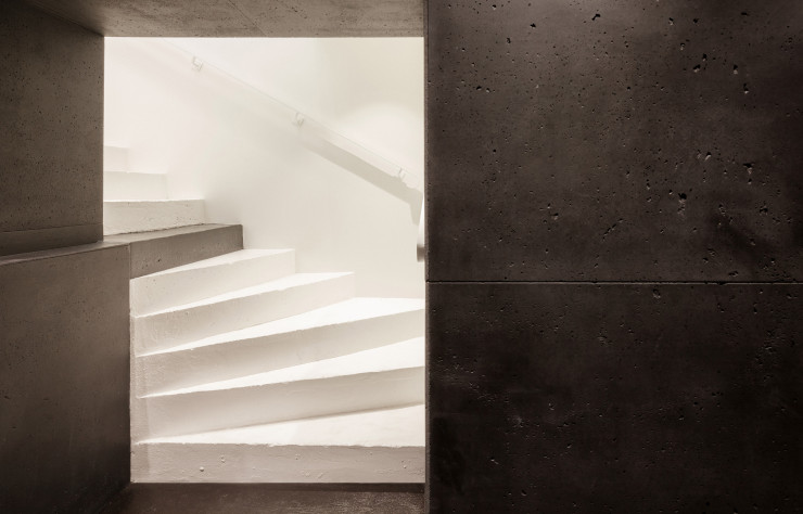 Ponctué par une marche béton millimétrique, l’escalier en métal thermolaqué mène au sous-sol nettement plus feutré.