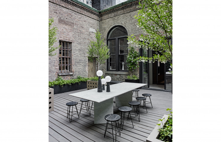 Star de la terrasse typiquement new-yorkaise, un prototype de table en marbre gris avec des tabourets à l’assise en marbre noir. Posés dessus, photophores Neo.