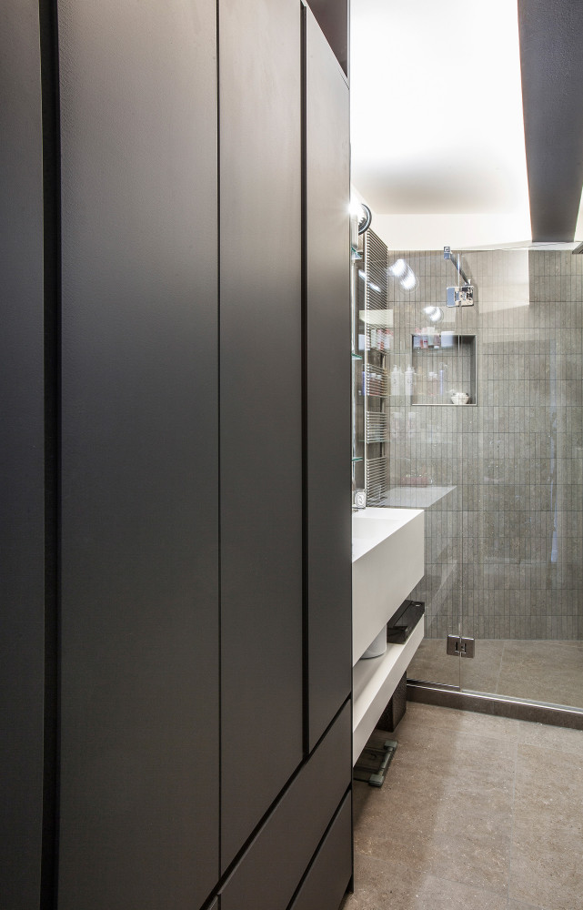 La salle de bains tranche avec le reste de l'appartement en adoptant des matériaux sombres.