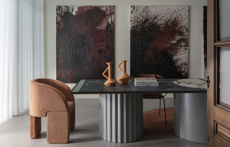 Autour de la table créée par Claude Cartier, fauteuil en peau ocre dessiné par Studiopepe pour Baxter. Deux carafes en céramique de l’atelier Polyedre. Sur le mur, deux toiles de Hermann Nitsch.