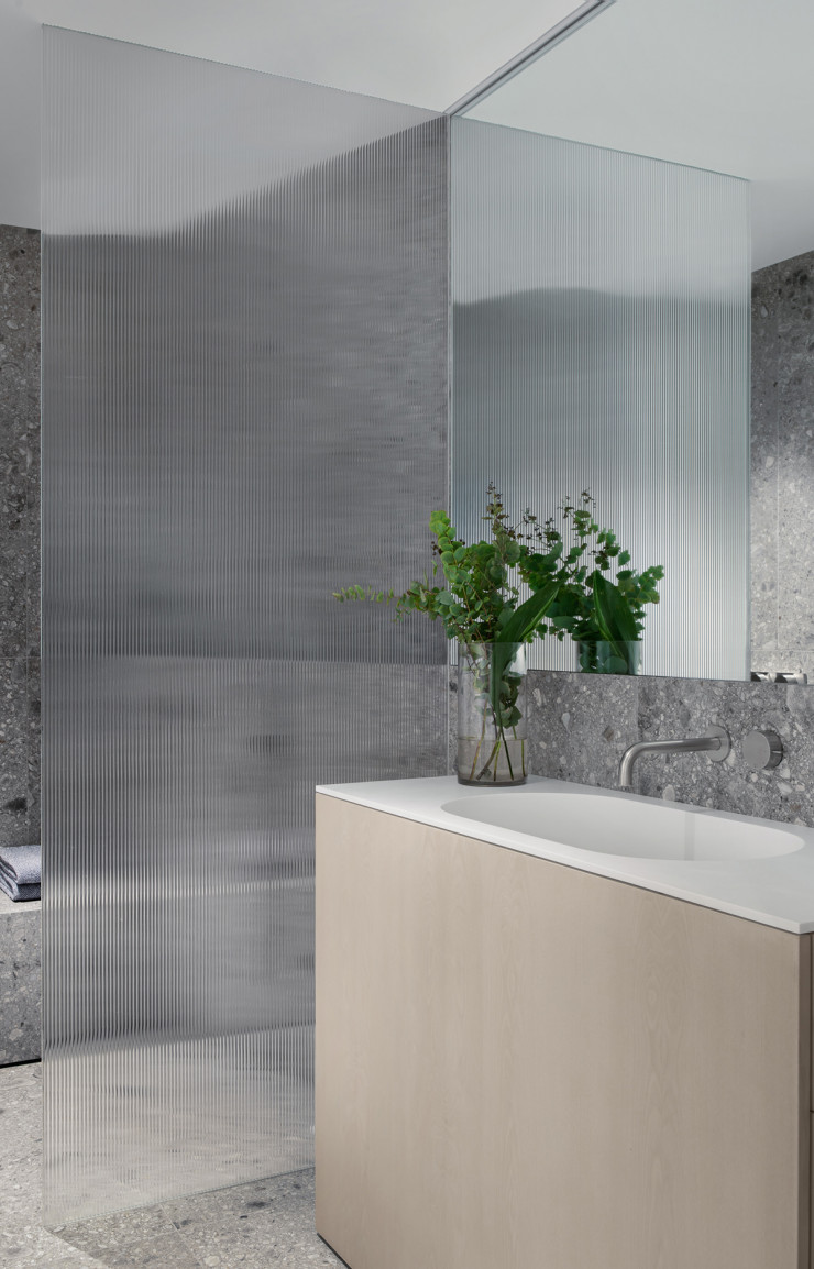Autre ambiance dans la salle de douche des parents, où des murs en obsidienne contrastent avec un meuble sur-mesure en chêne clair.