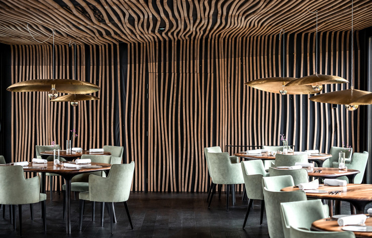 La salle du restaurant 2 étoiles est magnifiée par les suspensions de Paola Navone et accueille des tables en noyer de Valentin Loellmann.
