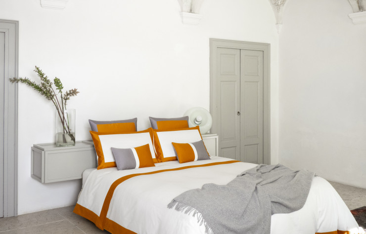 Une parure de lit grise, blanche et orange foncé. Des couleurs qui apportent une touche de pep’s dans une chambre.