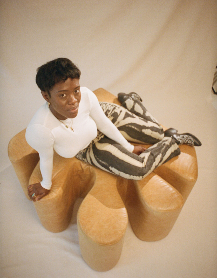 La designeuse Kusheda Mensah posant sur l’un de ses fauteuils modulaires.