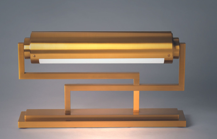 Le modèle 234, ici en finition dorée, est la matérialisation d’un nouveau concept d’éclairage de bureau pensé par Jean Perzel. Le cylindre de verre optique dépoli est cerclé d’un cache pivotant permettant une orientation plus précise de la lumière.