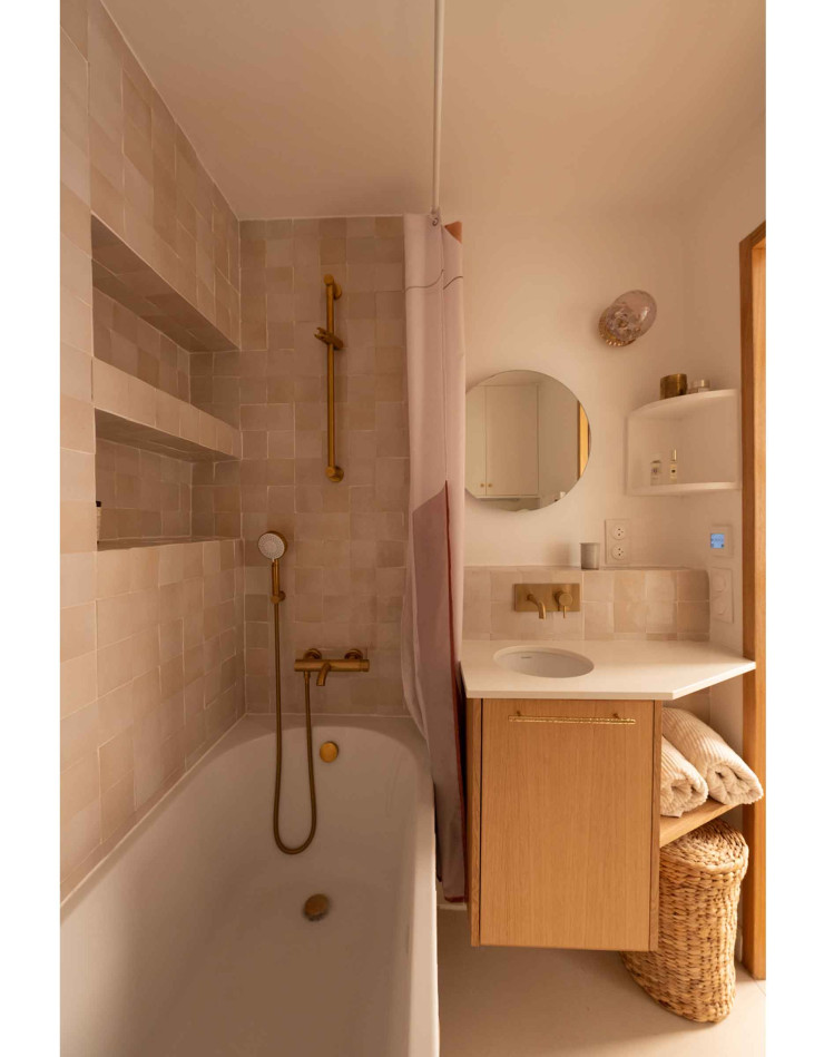 La salle de bain aux teintes roses poudrés est aménagée de telle sorte qu’elle offre la possibilité de prendre un bain. Un atout inestimable pour ce studio de 18m2.