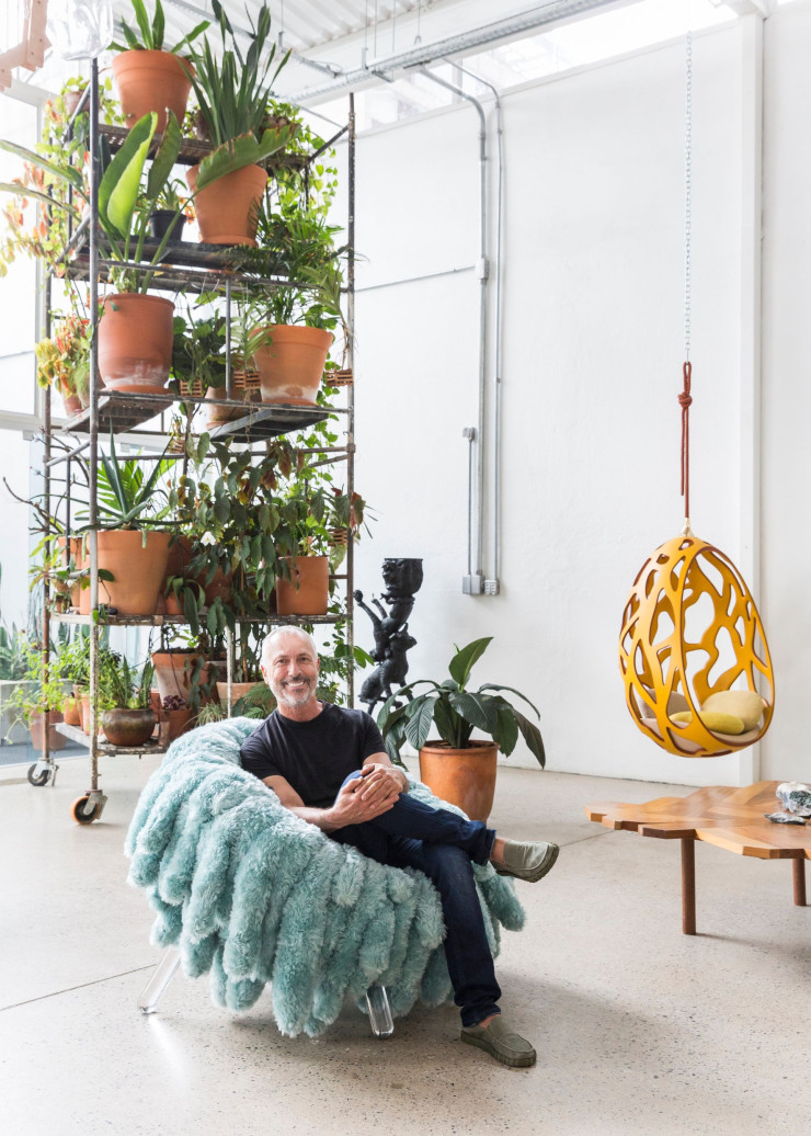 Humberto Campana, assis dans le fauteuil Abbraccio, créé en 2018 pour Giustini Stagetti, dans le nouveau studio Campana, installé dans un vaste et lumineux espace du quartier de Pompeia.