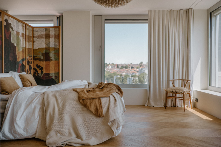 Comme tout l’appartement, la chambre jouit d’une magnifique vue sur la ville. Au plafond, le lustre Poliedri de Carlo Sacarpa. ©Julien Hay