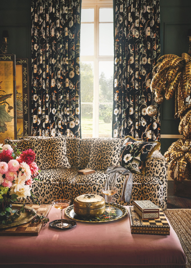 Dans un salon à l’ambiance bohème toute britannique canapé en imprimé léopard Mimi Velvet Tan et rideaux en tissu fleuri Euphoria Velvet Secret Garden (Temperley London x Romo).