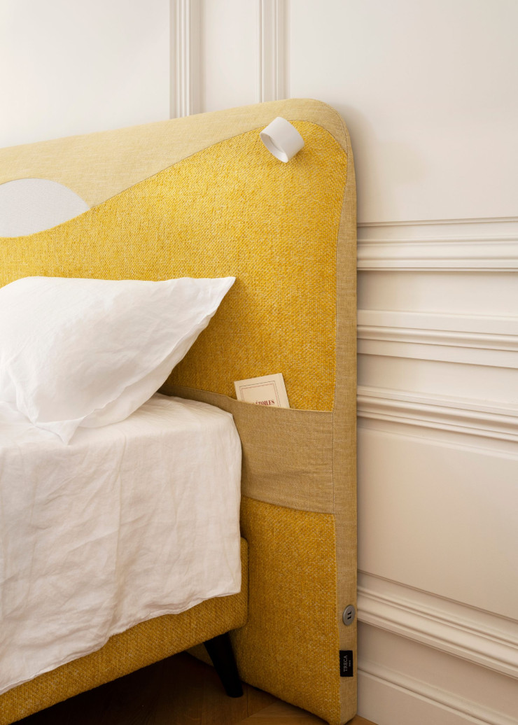 La tête de lit existe en cinq camaïeux (beige, noir, vert, gris et jaune) et intègre en option des luminaires à LED, des prises USB et des pochettes de rangement.
