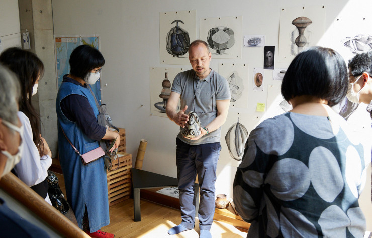 Lors des « Jeudis de la Villa », les studios des résidents sont ouverts au public. Ici, Gérald Vatrin, artisan verrier et lauréat 2023 en métiers d’art, explique son projet de recherche à des visiteurs attentifs.