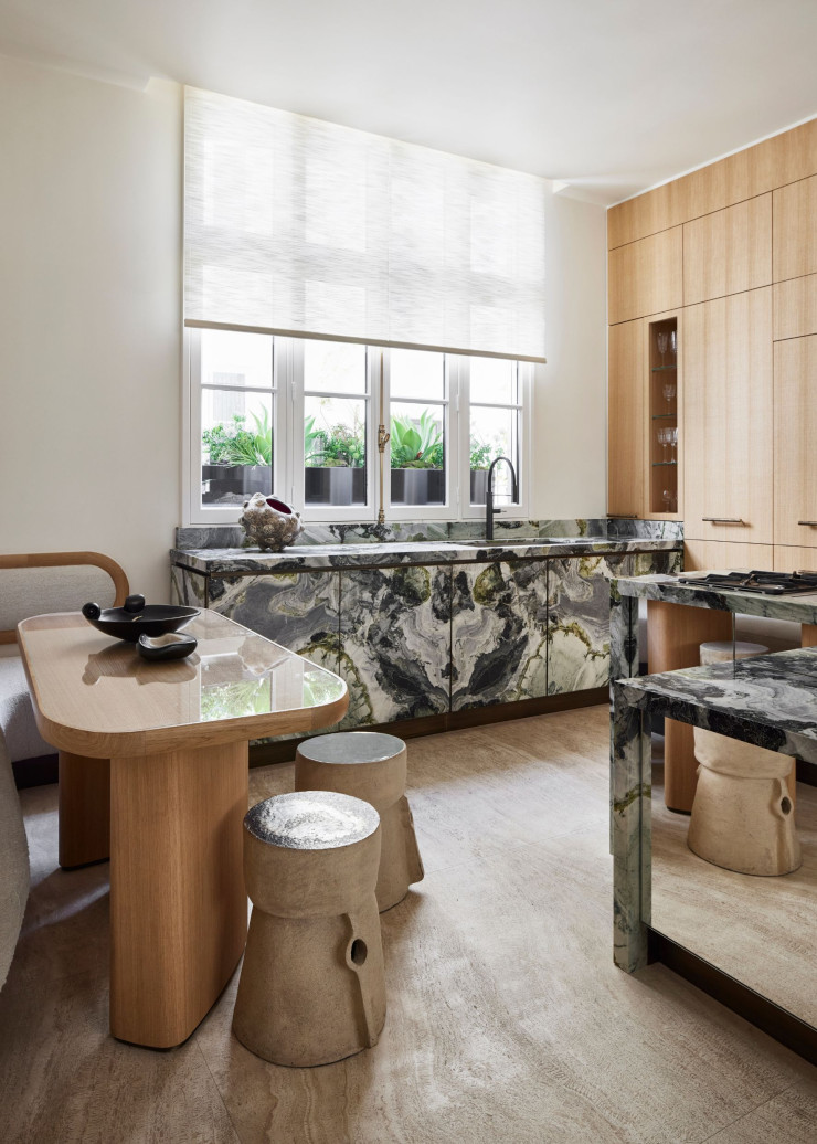 Stéphanie Coutas imagine une cuisine en marbre White Beauty et des armoires en chêne, associées à une table et à des tabourets en grès émaillé de Marc Albert.