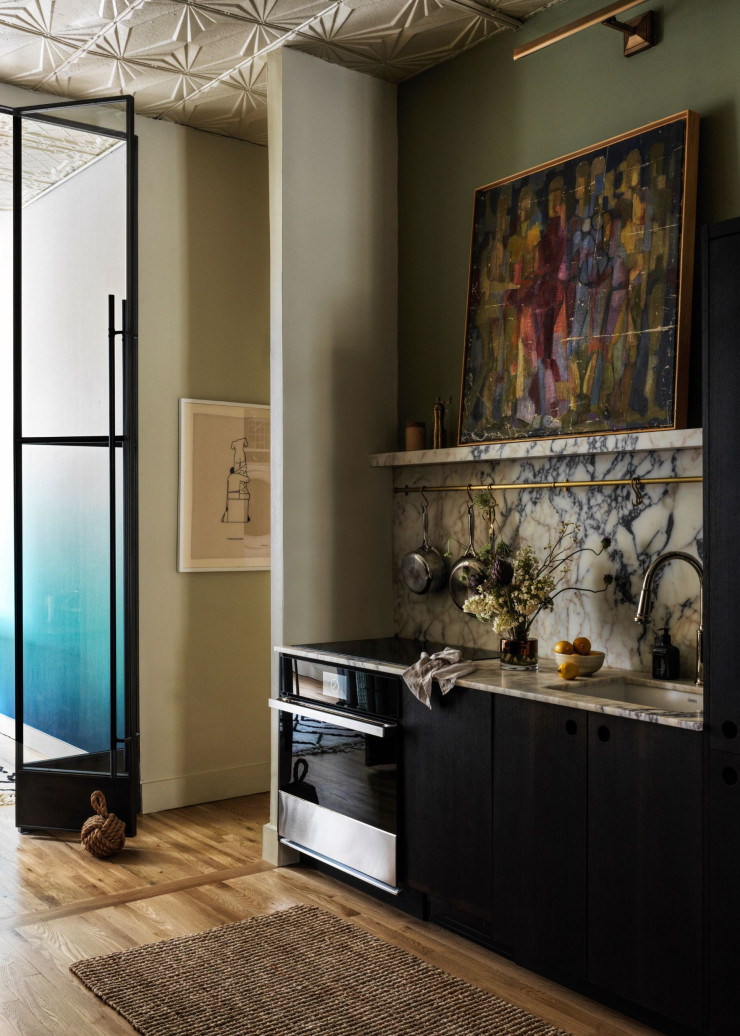 La cuisine ouverte est meublée de placards Reform. Plan de travail et crédence en marbre Arabescato violet. Sur l’étagère est posée une oeuvre acquise à Francfort. Dans le couloir, au mur, dessin de Sergio Membrillas.