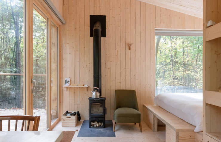 À l’intérieur, déco minimaliste et grandes baies vitrées pour admirer la beauté de la forêt.