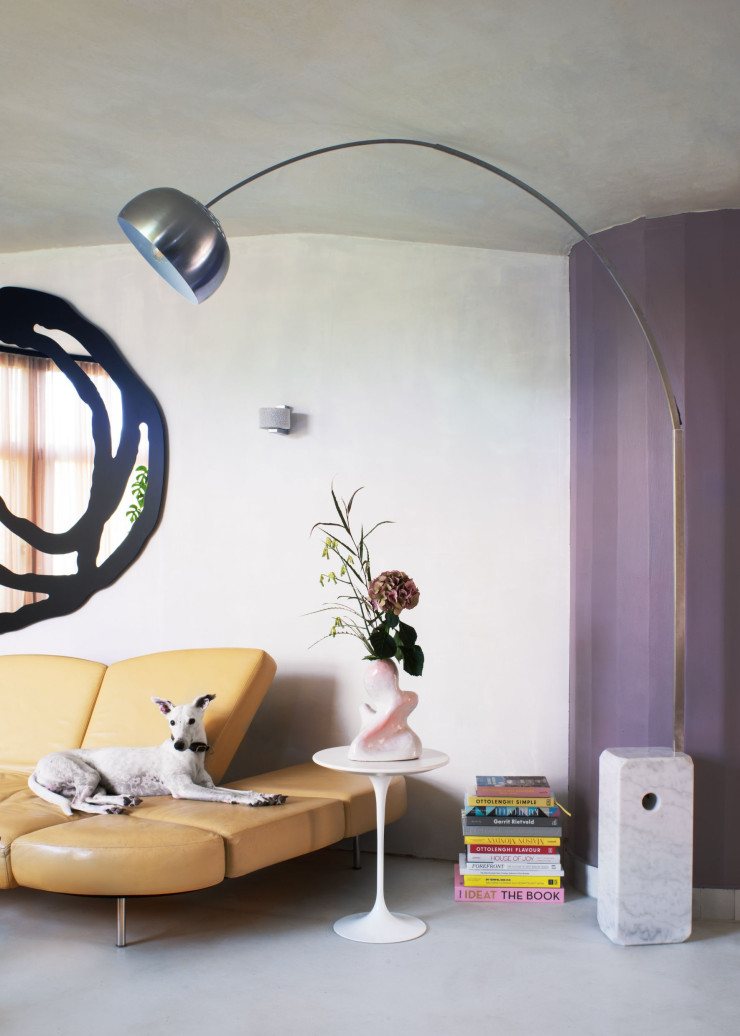 Dans le salon principal de Mia Martin, le chien Vincent est couché sur le canapé en cuir Flap, design Francesco Binfaré (Edra). Petite table Tulip, design Eero Saarinen (Knoll). Lampadaire Arco, design Achille et Pier Giacomo Castiglioni (Flos). Au mur, miroir Sweet, design Paola Navone (Gervasoni).