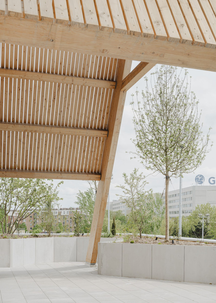 Une toiture à deux pentes en bois s’installe tel un totem sur la grande terrasse en belvédère sur l’espace public.