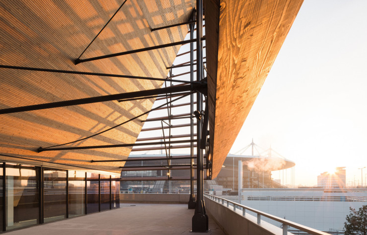 Le bâtiment fait face au Stade de France, avec lequel il établit un dialogue grâce à une passerelle qui enjambe l’autoroute.