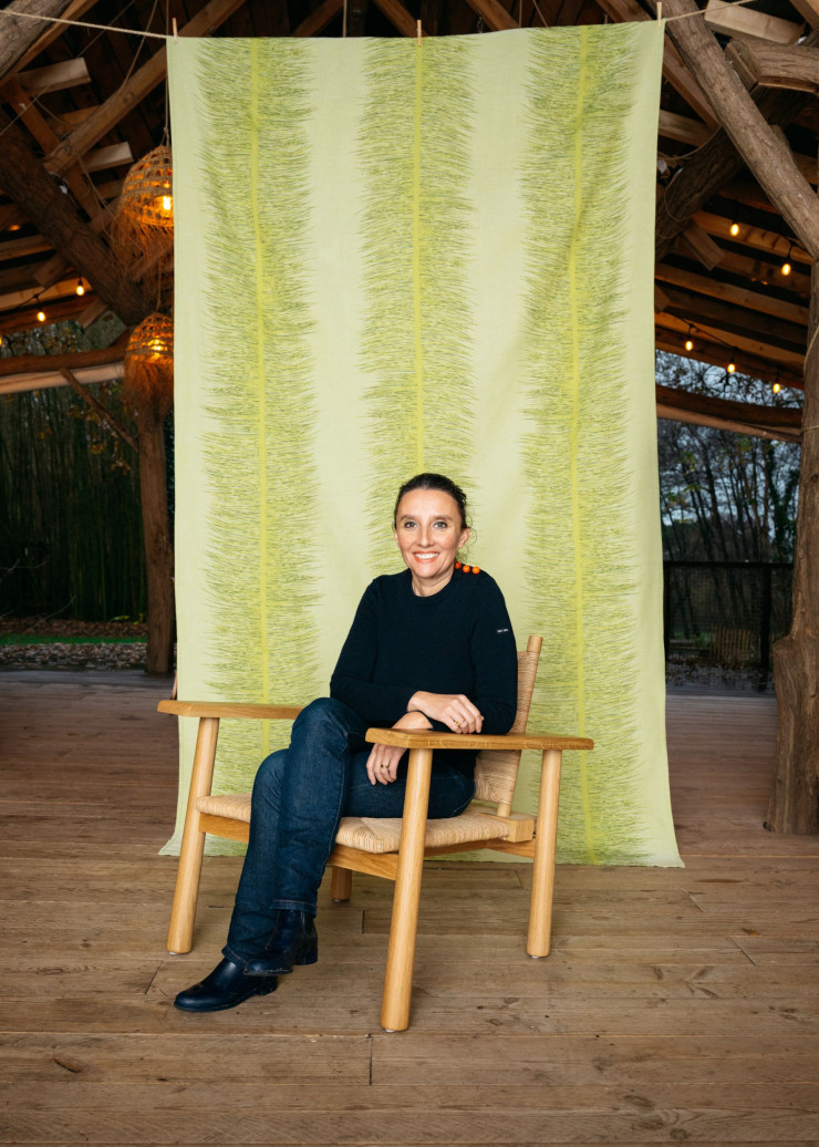 Élise Fouin pose devant la nappe Aiguille de la collection « Pinaceae », qui reproduit la structure des branches de pin (Tissage Moutet).