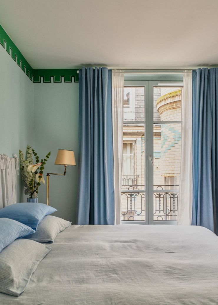 Dans la chambre, la tête de lit a été réalisée avec des draps hérités de l’arrière-grand-mère d’Anaïs. Parure de lit Merci. Doubles rideaux Arne Aksel. Lampadaire chiné chez Gasoline Brocante. Frise MUES Design.