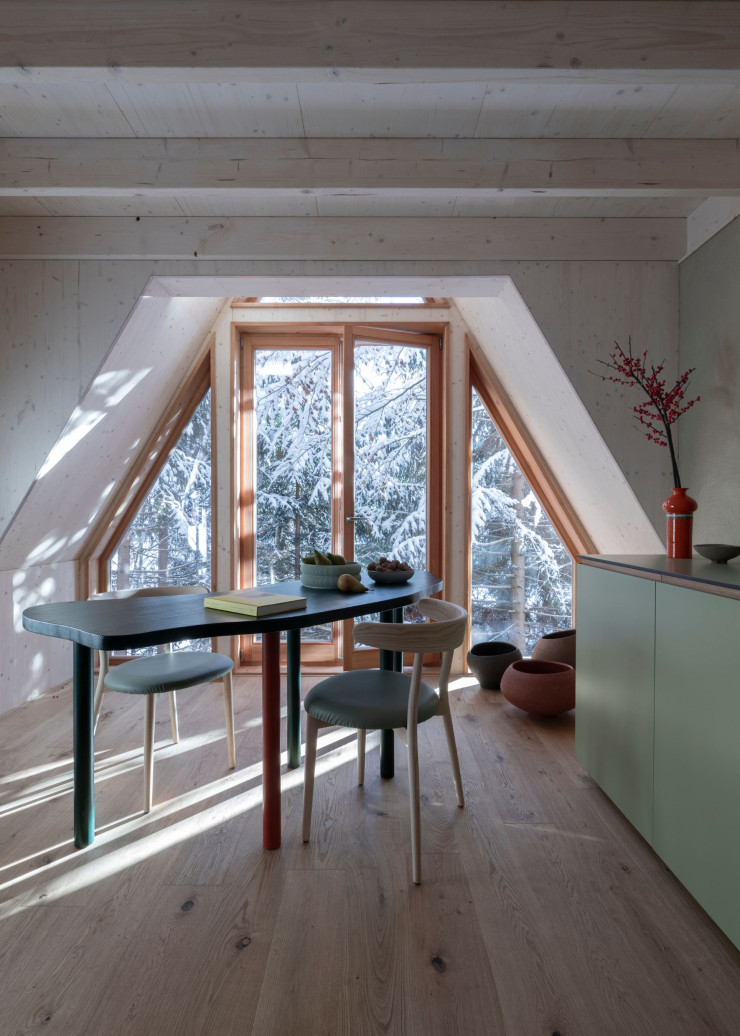 Au rez-de-chaussée, dans la cuisine signée Alta Cucine, la table de salle à manger réalisée sur mesure par Beltrame Studio reproduit la forme du lac de Predil, situé non loin. Bols à fruits Sheyn. Chaises en frêne Bio, de Balutto Associati (Livoni 1895). Au sol, vases en céramique « Nido Collection » (Studio Terrae).