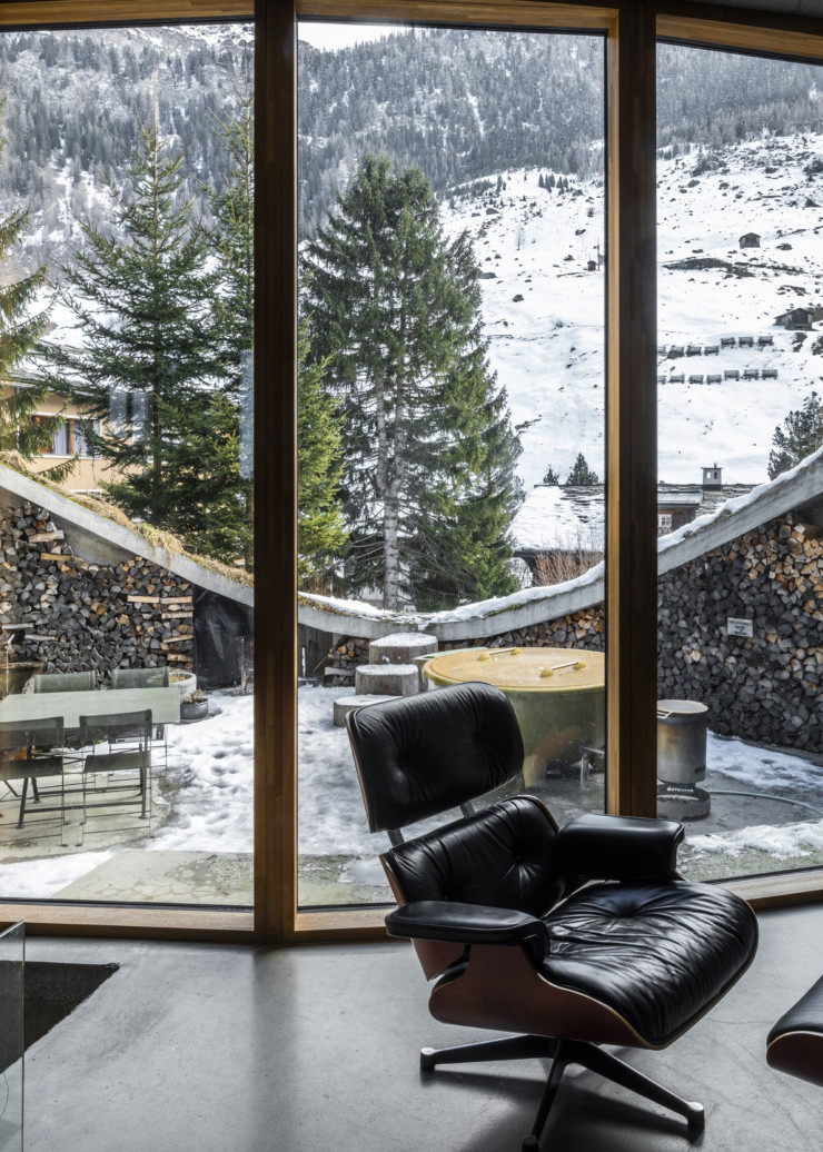 Le salon et son iconique Lounge Chair, de Charles&Ray Eames, devant une large baie vitrée ouverte sur la terrasse.