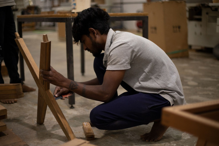 Étape d’encollage à la main sur un piétement de l’Office Armchair X Leg du projet « Chandigarh ».