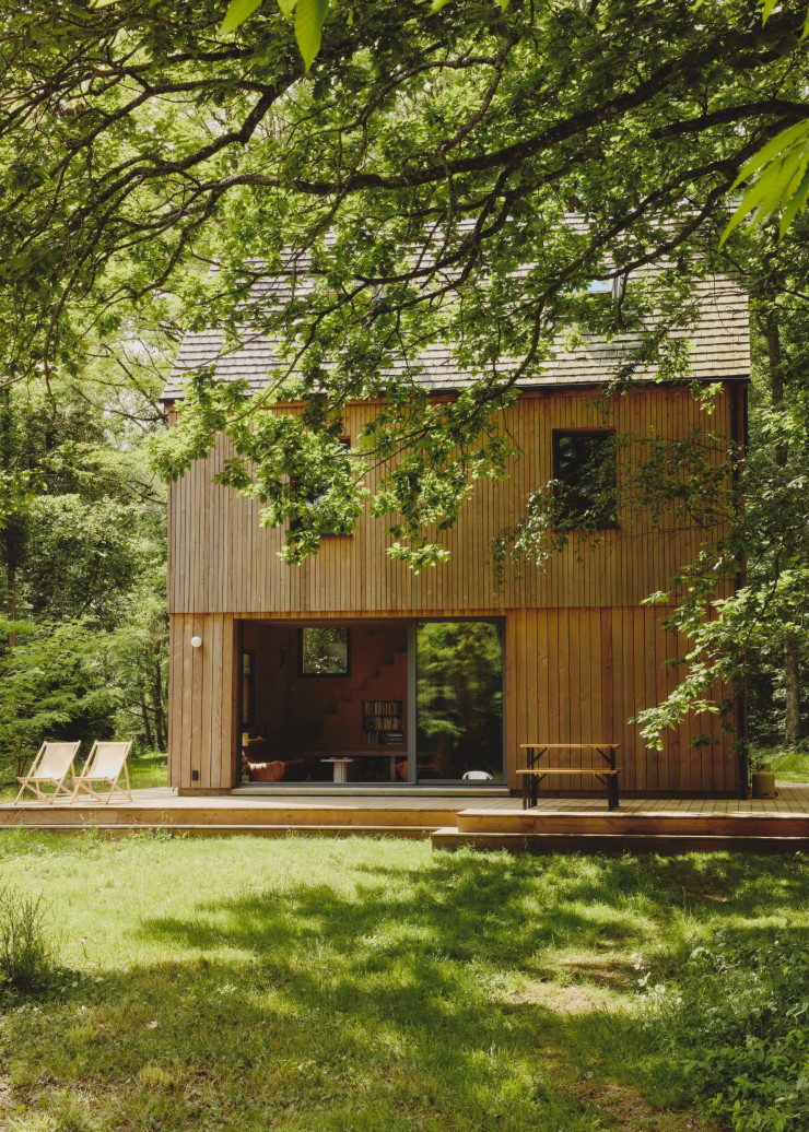 Le chalet tout en bois, aux lignes sobres, se glisse au milieu de la forêt, au cœur du Parc naturel régional du Perche. Son bardage Douglas prend des teintes différentes au fil du temps. À quelques pas, un hamac suspendu entre les arbres invite au lâcher-prise.