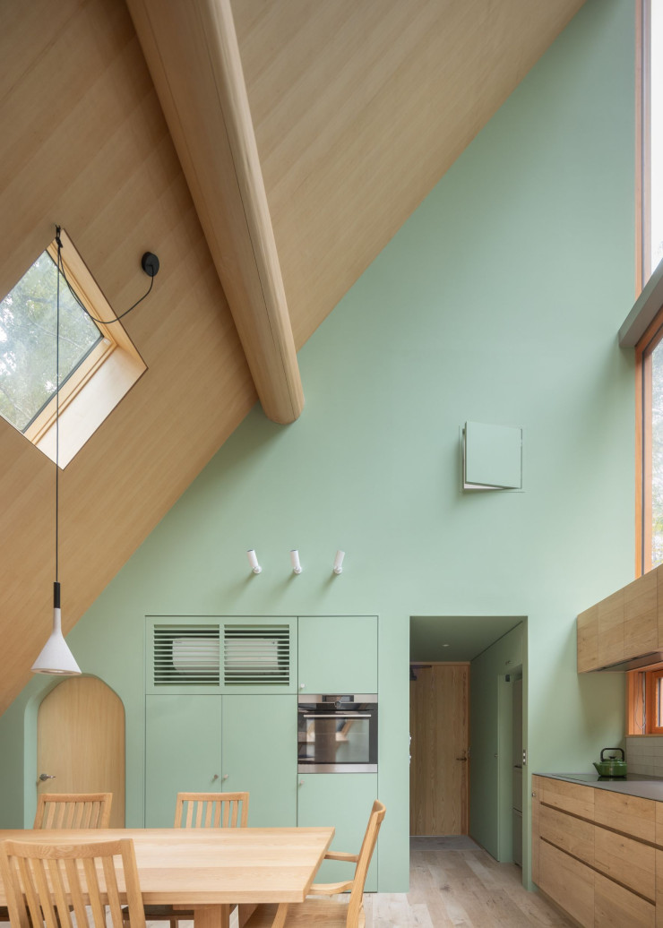 Dans la cuisine, une petite fenêtre en hauteur est dissimulée dans le mur par un volet en mélèze. Elle permet à la fille du couple d’embrasser la vue sur les espaces de vie depuis sa chambre, à l’étage.