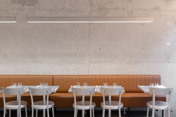 Le restaurant de burgers Le Ruisseau, dans le XIVe arrondissement de la capitale, mise sur des éléments bruts, comme le mur en béton, associé à une banquette façon diner américain.