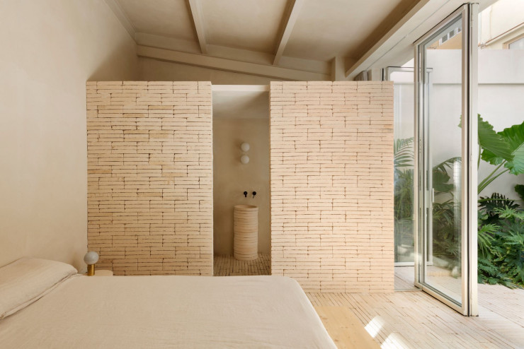 Dans la chambre, sommier en bois fabriqué sur mesure. Table de chevet conçue à partir de disques en céramique empilés. Lampe sans fil Dipping Light, de Jordi Canudas (Marset, 2019).