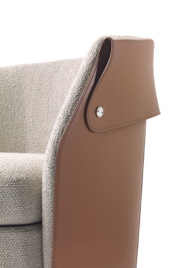 Toute la collection, comprenant un fauteuil et un pouf, présente un dossier extérieur en cuir de sellerie évoquant un col.