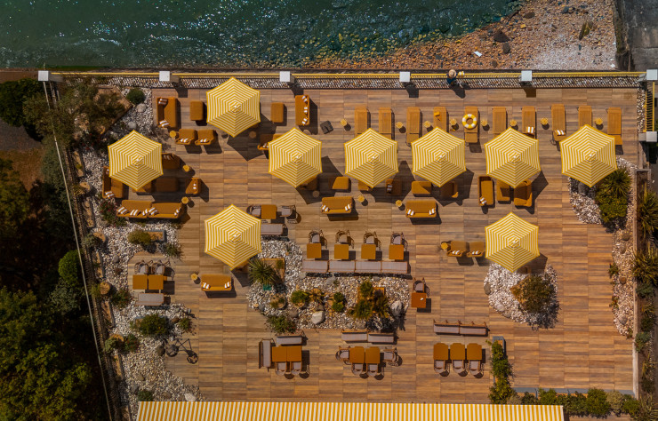 Une façade jaune pâle, des parasols rayés, du rotin et l’océan en ligne de mire : à La Rochelle, Les Brises assume le grand bain balnéaire.